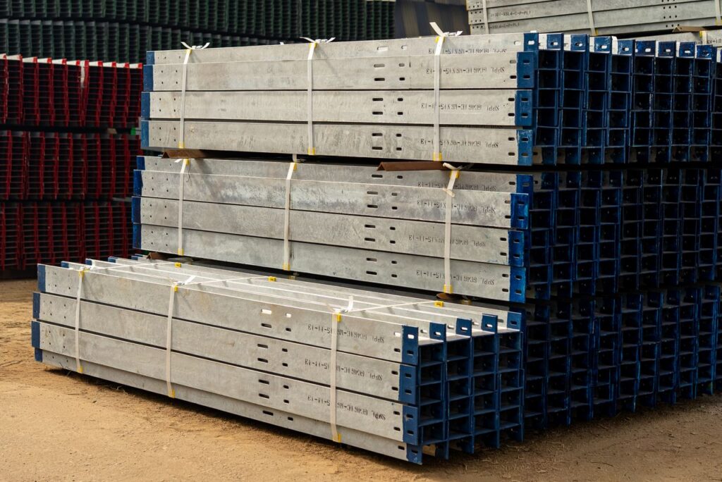 Neatly stacked metal beams in an outdoor industrial yard under daylight.